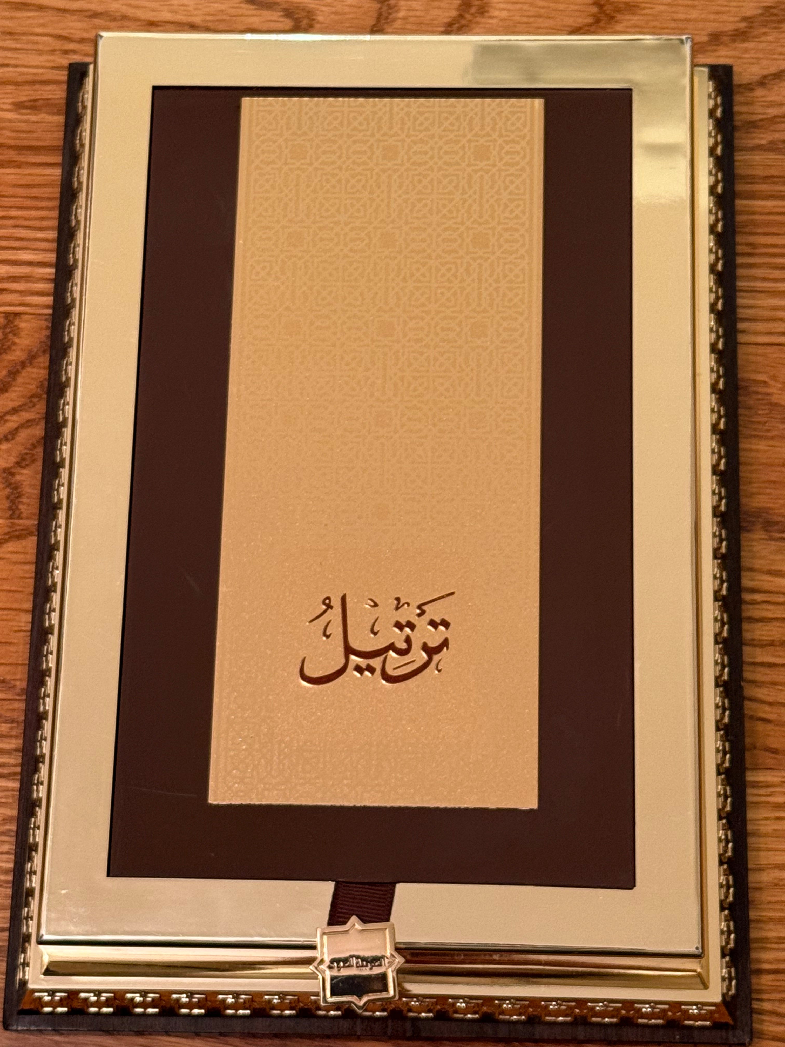 Decorative book with gold cover and Arabic text on a wooden surface