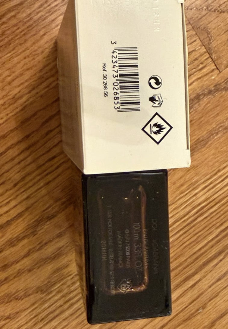 Bar code and warning label on a cardboard box with a black rectangular object underneath on a wooden surface.