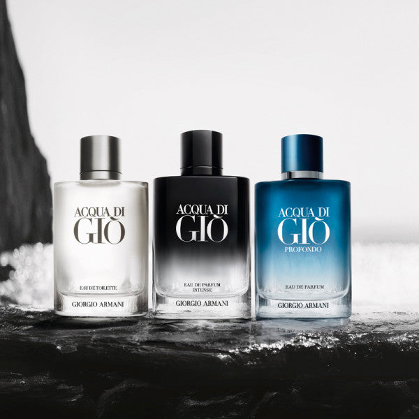 Three bottles of Acqua di Giò by Giorgio Armani on a dark surface with a blurred background.
