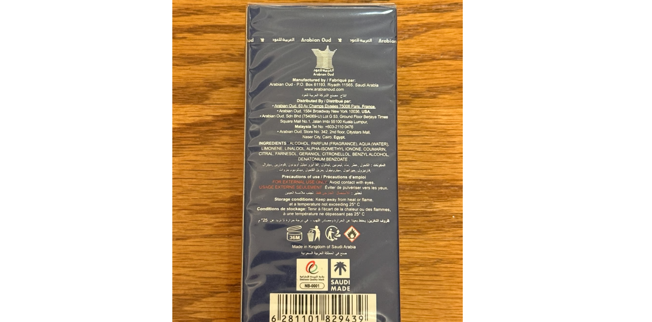 Back view of a product packaging with text and logos on a wooden surface