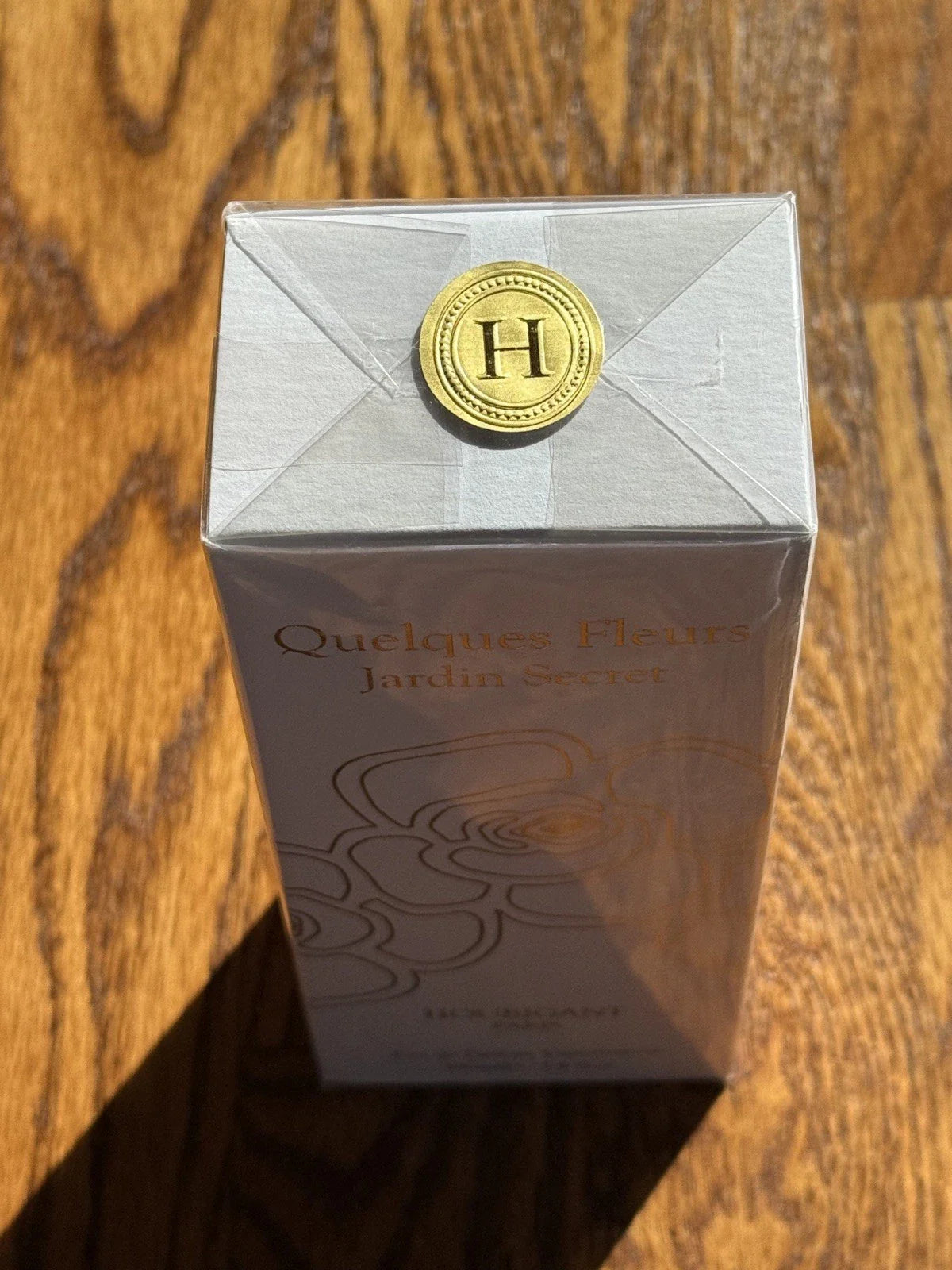 Perfume box with a gold cap on a wooden surface