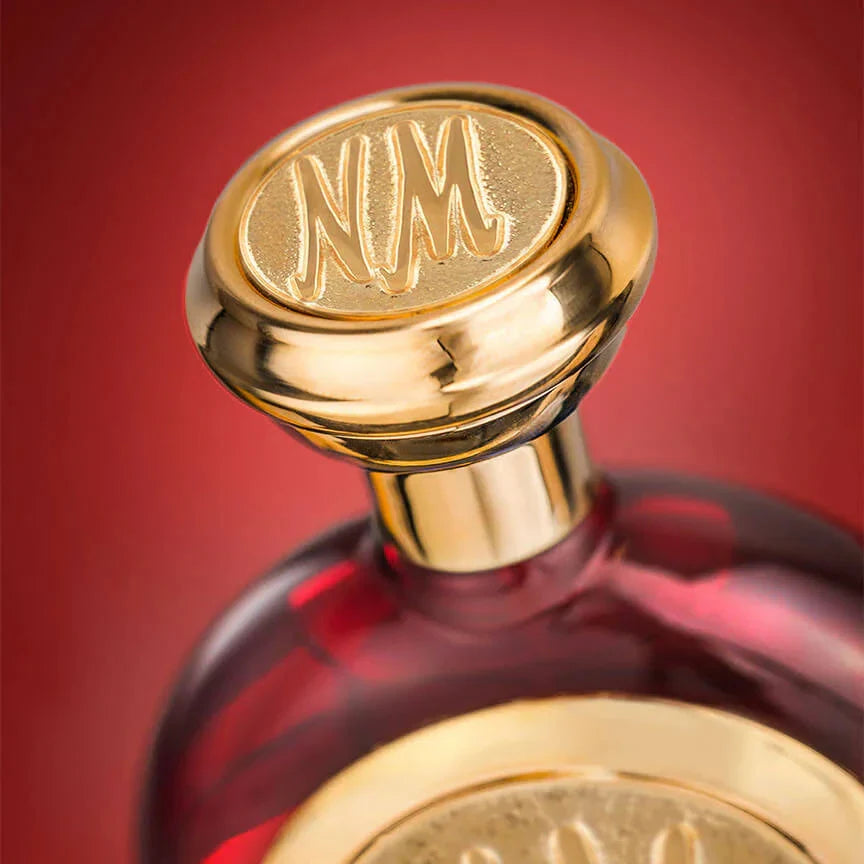 Close-up of a perfume bottle with a gold cap and red background